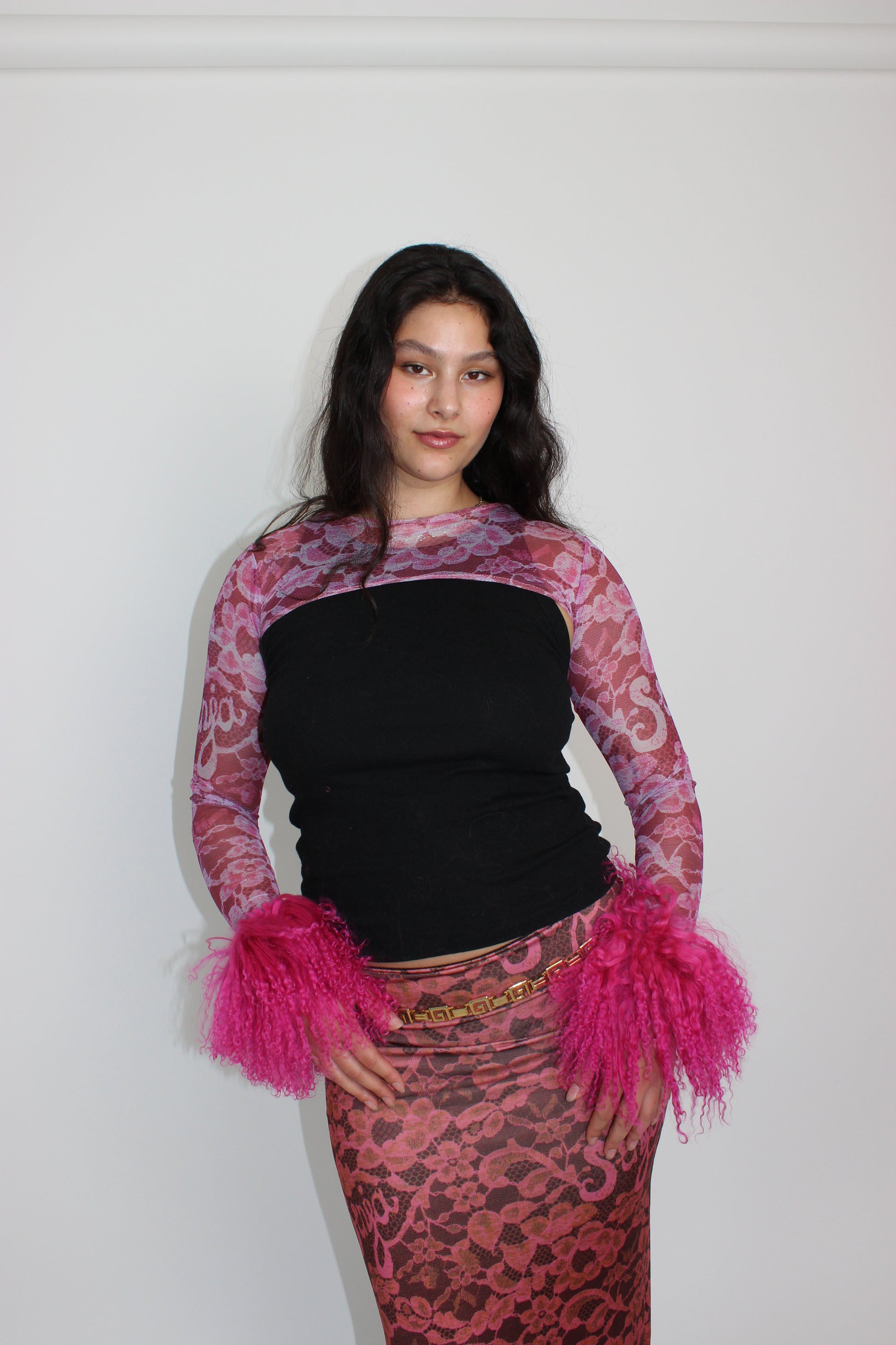 Person wearing a black top with pink and purple sleeves and skirt on a white background